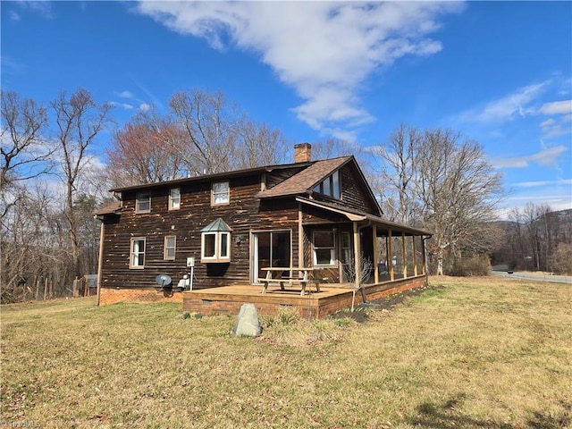 view of front of house with a sunroom, a chimney, a deck, and a front yard