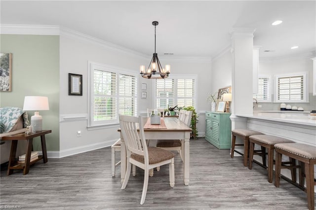 dining room with dark hardwood / wood-style flooring, crown molding, ornate columns, and an inviting chandelier