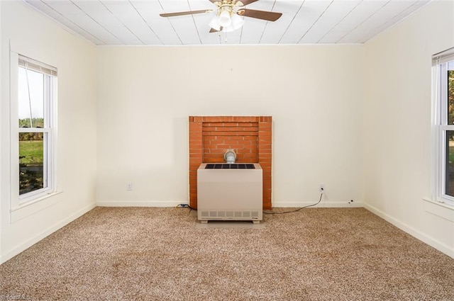 carpeted spare room with heating unit, ceiling fan, crown molding, and a healthy amount of sunlight