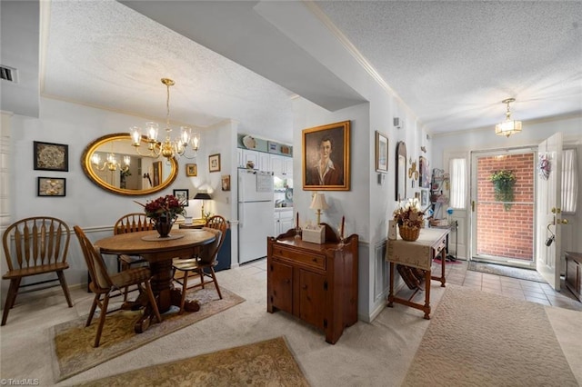 dining room featuring a textured ceiling, a chandelier, light colored carpet, crown molding, and baseboards