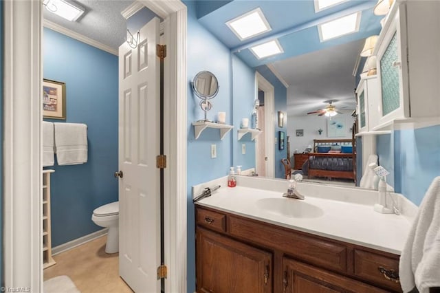 ensuite bathroom featuring toilet, vanity, a ceiling fan, and baseboards