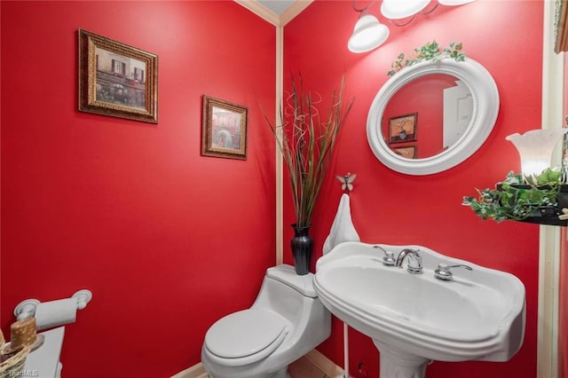 half bath with a sink, toilet, and baseboards