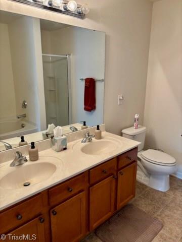 full bathroom featuring toilet, double vanity, a sink, and a shower with door