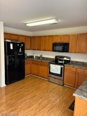 kitchen featuring brown cabinets, light wood finished floors, and black appliances