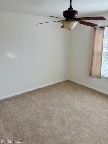 carpeted empty room featuring baseboards and a ceiling fan