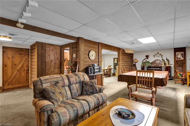 carpeted living room with a paneled ceiling, wooden walls, track lighting, and billiards