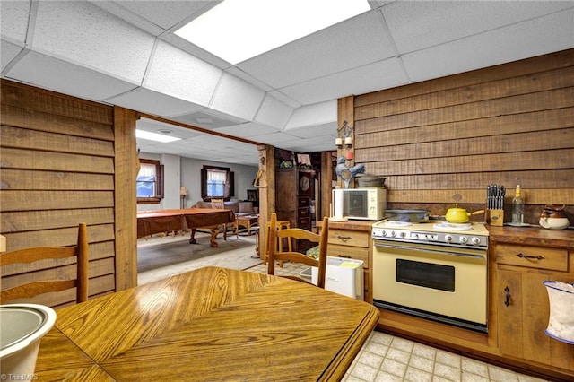 kitchen featuring wood walls, a drop ceiling, pool table, and white gas range