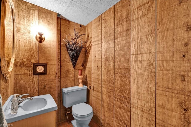 bathroom with vanity, wooden walls, and toilet