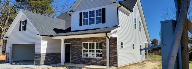 view of front facade featuring stone siding, a shingled roof, and a garage