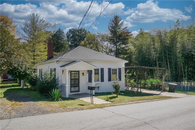 bungalow featuring a shingled roof, fence, a front lawn, and stucco siding