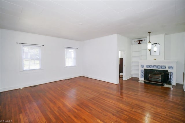 unfurnished living room featuring dark wood-type flooring and a tile fireplace