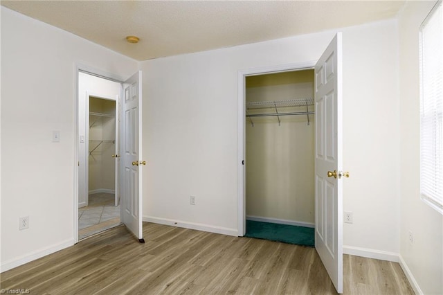 1309 Jackson St, Burlington, NC 27217 - unfurnished bedroom with light wood-type flooring, a walk in closet, a closet, and baseboards
