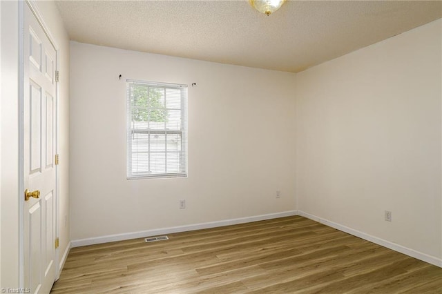 1309 Jackson St, Burlington, NC 27217 - empty room with light wood-style flooring, baseboards, and a textured ceiling