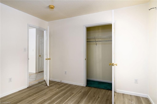 1309 Jackson St, Burlington, NC 27217 - unfurnished bedroom with wood finished floors, a closet, baseboards, and a textured ceiling
