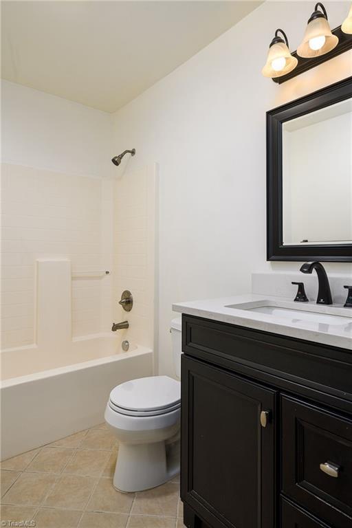 1309 Jackson St, Burlington, NC 27217 - full bath featuring toilet, vanity, shower / washtub combination, and tile patterned flooring