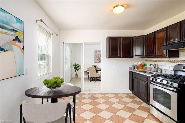 1309 Jackson St, Burlington, NC 27217 - kitchen with stainless steel gas stove, a sink, under cabinet range hood, dark brown cabinetry, and light countertops