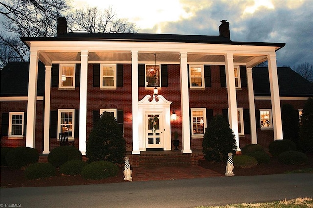 neoclassical / greek revival house with brick siding and a chimney