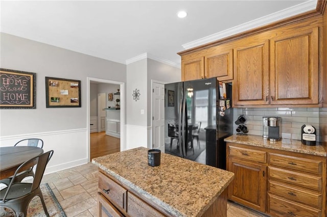 641 Doe Run Dr, Kernersville, NC 27284 - kitchen featuring black fridge with ice dispenser, brown cabinetry, tasteful backsplash, crown molding, and light stone countertops