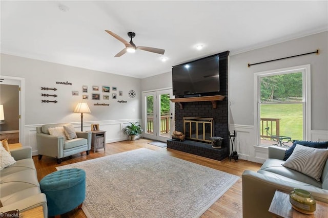 641 Doe Run Dr, Kernersville, NC 27284 - living area featuring a ceiling fan, crown molding, a brick fireplace, a wainscoted wall, and wood finished floors