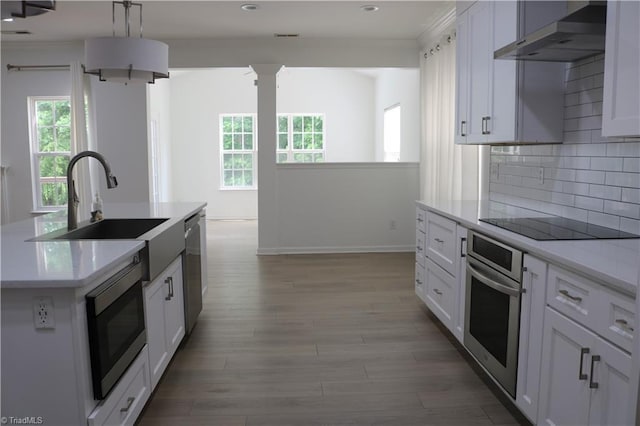6215 Glen Way Dr, Winston-Salem, NC 27107 - kitchen featuring appliances with stainless steel finishes, extractor fan, light countertops, decorative backsplash, and light wood-style floors
