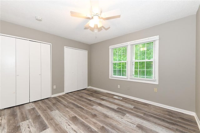 311 Salisbury St Unit 50, Kernersville, NC 27284 - unfurnished bedroom featuring multiple closets, baseboards, wood finished floors, and a ceiling fan