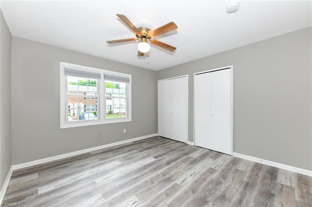 311 Salisbury St Unit 50, Kernersville, NC 27284 - unfurnished bedroom with multiple closets, wood finished floors, baseboards, and a ceiling fan
