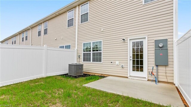back of property featuring central AC unit, a patio, and a lawn