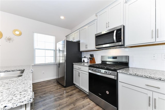 kitchen featuring white cabinetry, light stone countertops, dark hardwood / wood-style floors, and appliances with stainless steel finishes