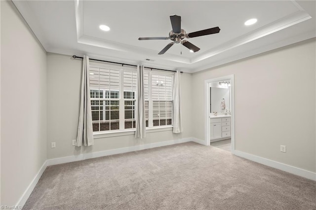 unfurnished room with carpet flooring, a ceiling fan, a tray ceiling, and baseboards