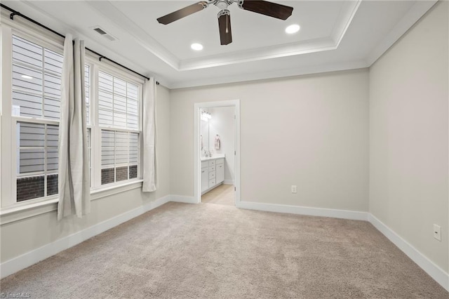 unfurnished bedroom with a tray ceiling, baseboards, light colored carpet, and visible vents