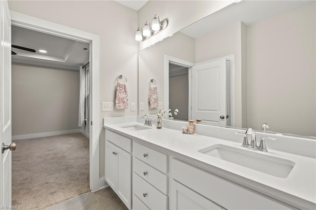 bathroom with double vanity, a sink, tile patterned flooring, and baseboards