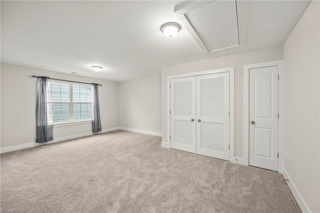 unfurnished bedroom featuring attic access, baseboards, a closet, and carpet