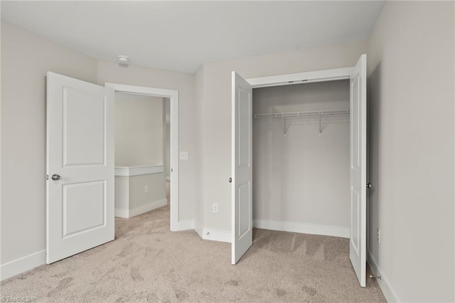 unfurnished bedroom with a closet, carpet flooring, and baseboards