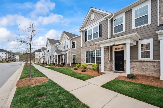 multi unit property featuring a residential view, brick siding, and a front lawn