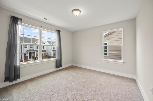 empty room featuring baseboards, visible vents, and carpet