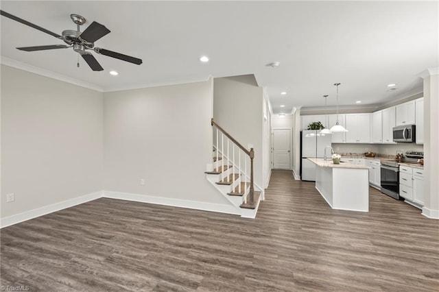 kitchen featuring open floor plan, appliances with stainless steel finishes, dark wood-type flooring, and crown molding