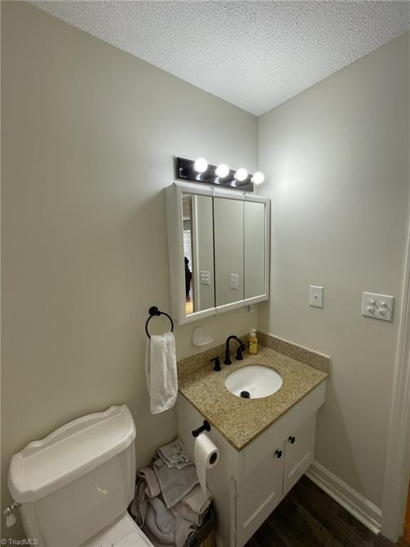 bathroom with vanity, wood-type flooring, a textured ceiling, and toilet