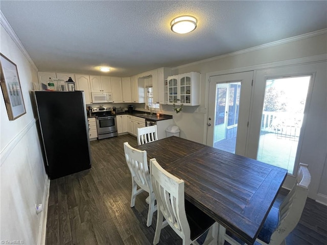 dining room featuring a textured ceiling, dark wood-type flooring, crown molding, and sink