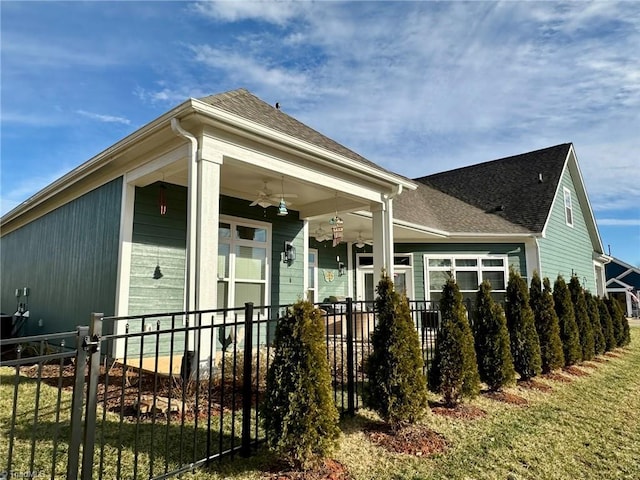 view of front of house featuring a fenced front yard, a porch, a shingled roof, and a ceiling fan