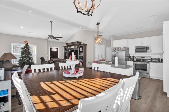 dining room with ceiling fan with notable chandelier, lofted ceiling, and light wood-type flooring