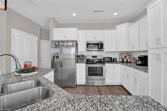 kitchen featuring light stone countertops, stainless steel appliances, sink, dark hardwood / wood-style floors, and white cabinetry