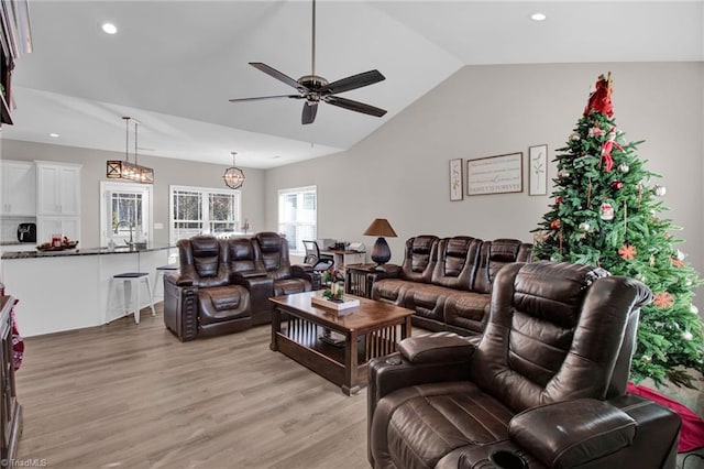 living room with light wood-type flooring, vaulted ceiling, ceiling fan, and sink