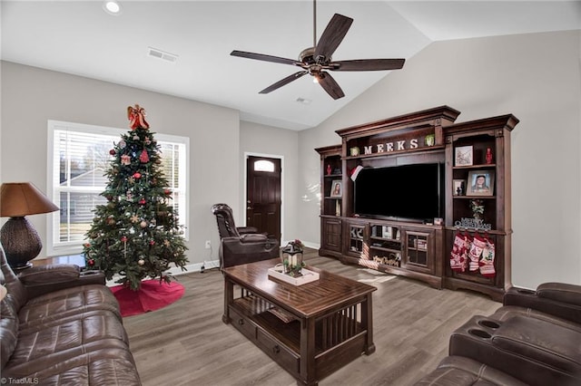 living room with ceiling fan, light hardwood / wood-style floors, and vaulted ceiling