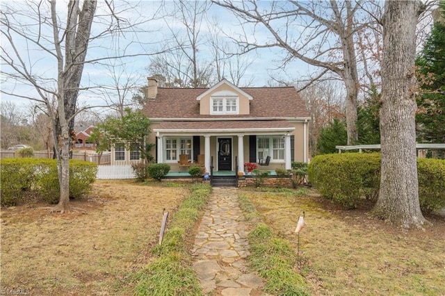 cape cod home with a front yard and covered porch