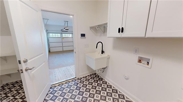 laundry area with washer hookup, a sink, baseboards, cabinet space, and tile patterned floors