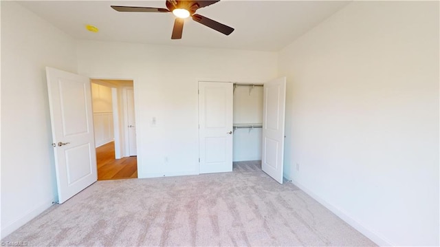 unfurnished bedroom with a closet, light colored carpet, ceiling fan, and baseboards