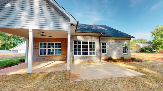 back of house featuring brick siding, roof with shingles, a ceiling fan, and a patio