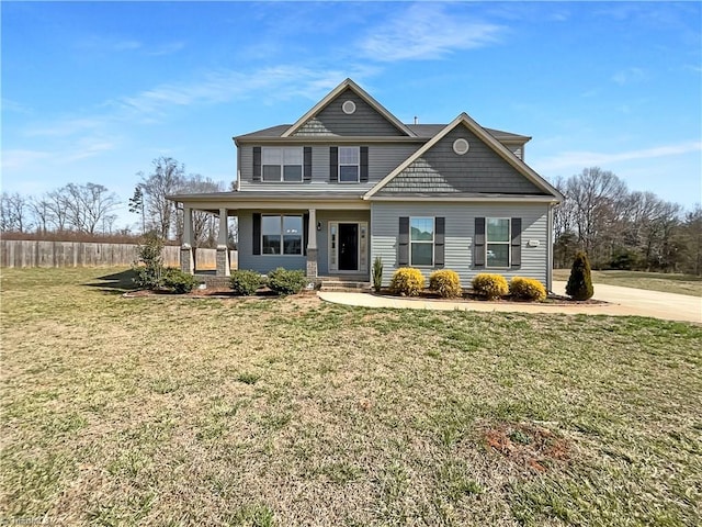 view of front facade with a front yard, covered porch, and fence