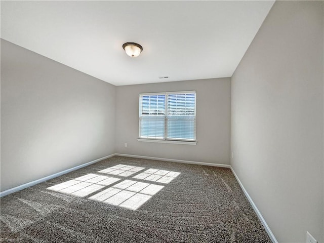 spare room with carpet floors, visible vents, and baseboards