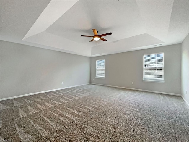 carpeted empty room with a textured ceiling, a raised ceiling, a ceiling fan, and baseboards